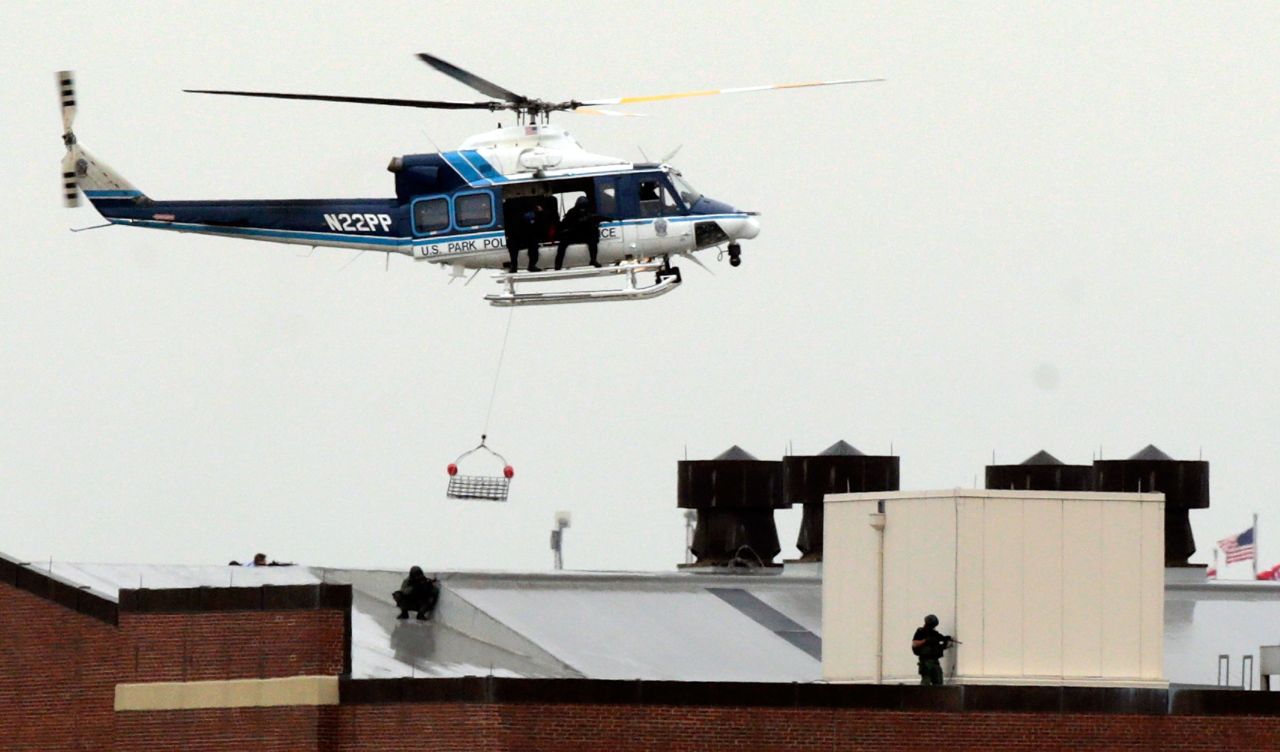 A police helicopter hovers above snipers on the roof of a building at the Washington Navy Yard.