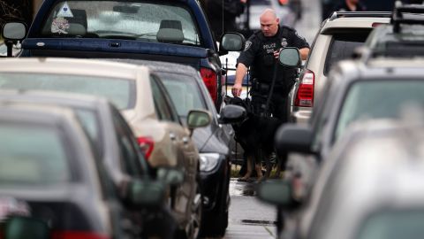 A police officer and police canine inspect vehicles in a parking lot outside the Washington Navy Yard.