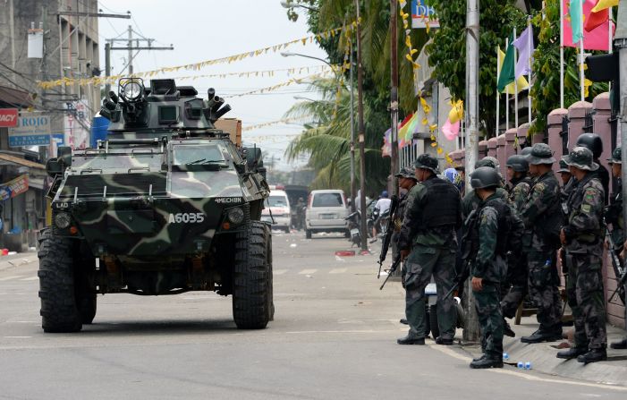 An armored personnel carrier passes by a group of soldiers. The Philippine military launched a helicopter assault on September 16 on Muslim rebels occupying parts of a major southern city.