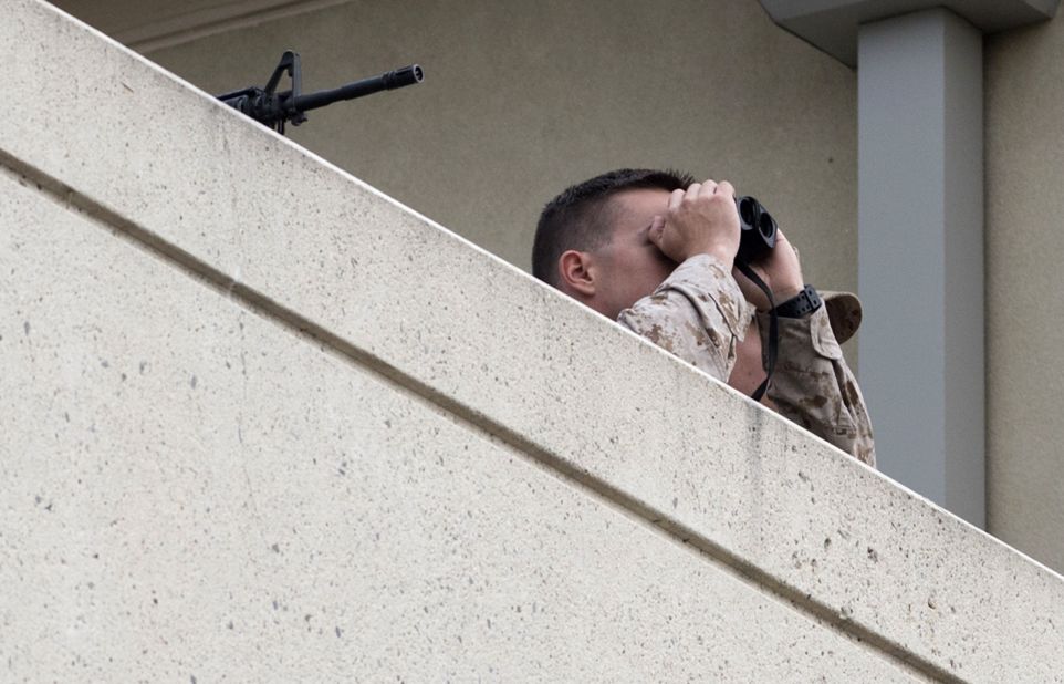 Military security observes the scene from a nearby rooftop.