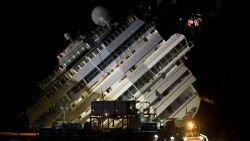 The Costa Concordia ship lies on its side on the Tuscan Island of Giglio, Italy, Monday, Sept. 16, 2013. Using a vast system of steel cables and pulleys, maritime engineers on Monday gingerly winched the massive hull of the Costa Concordia off the reef where the cruise ship capsized near an Italian island in January 2012. But progress in pulling the heavily listing luxury liner to an upright position was going much slower than expected. Delays meant the delicate operation — originally scheduled from dawn to dusk Monday — was not expected to be completed before Tuesday morning. (AP Photo/Andrew Medichini)