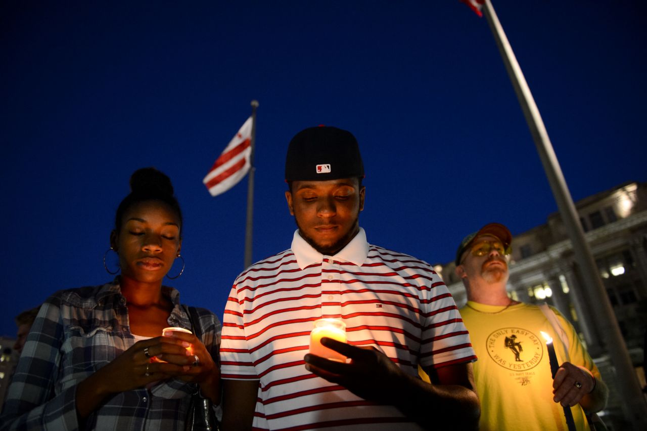 From left, Brittany Carter, Jibri Johnson and Bryan Beard attend a small candlelight vigil at Freedom Plaza in Washington on September 16.