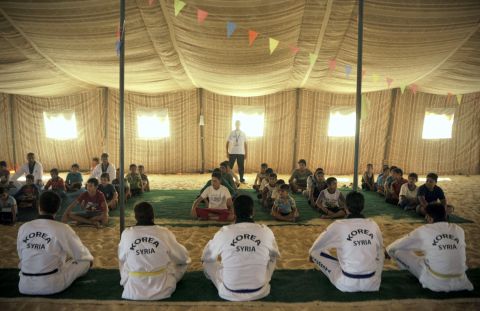 Syrian refugee children watch Korean and Syrian taekwondo instructors during training at the Zaatari refugee camp in Jordan in September 2013.