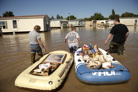 From left, Dale Reeves, Kathryn Reeves and Trent Mayes assist a family member by moving belongings from a flooded home in Evans, Colorado, on September 17.