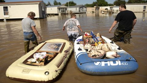 From left, Dale Reeves, Kathryn Reeves and Trent Mayes assist a family member by moving belongings from a flooded home in Evans, Colorado, on September 17.