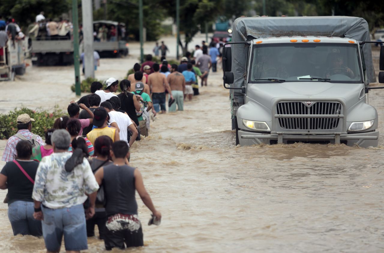 Residentes y turistas se mueven a través de las calles inundadas en Acapulco.