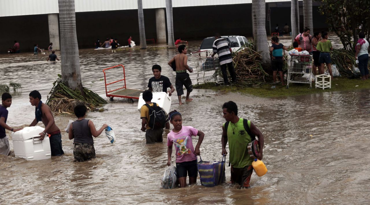 Los residentes llevan algunas de sus pertenencias a través de una vía inundada en Acapulco.