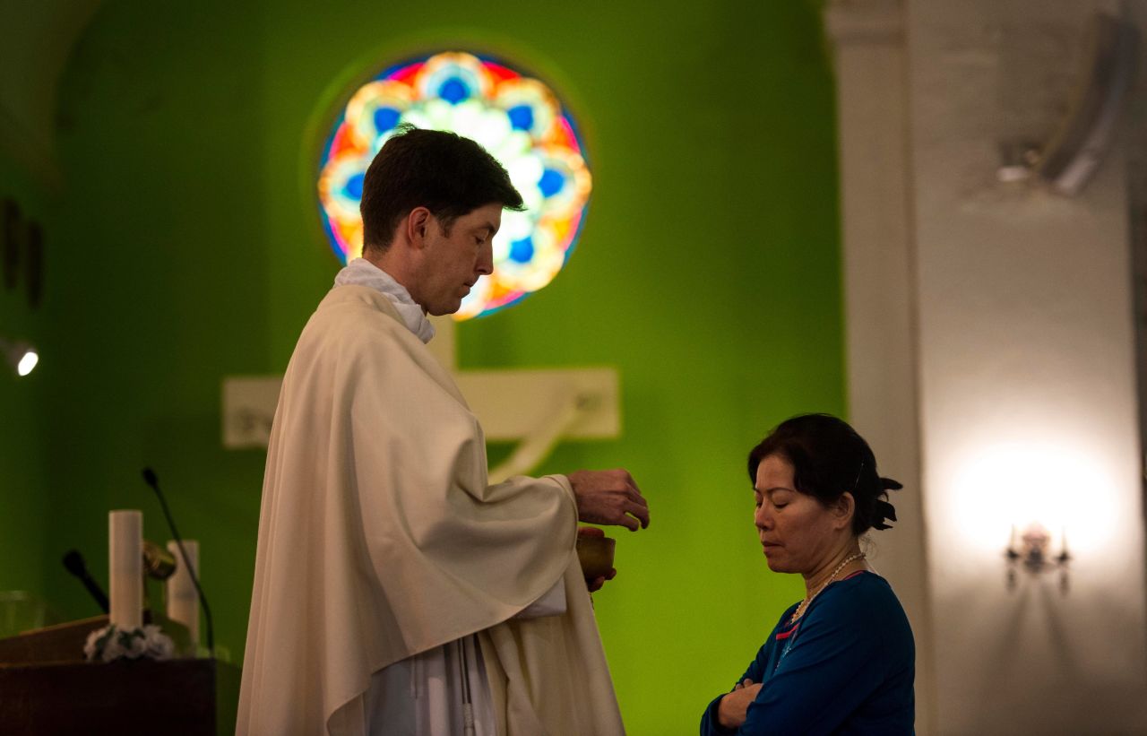 The Rev. Andrew Royals offers communion to Vinh Tran during a Catholic Mass at the St. Vincent De Paul Church on September 16. A prayer for the shooting victims was held at the church, which is just blocks away from the site of the violence.