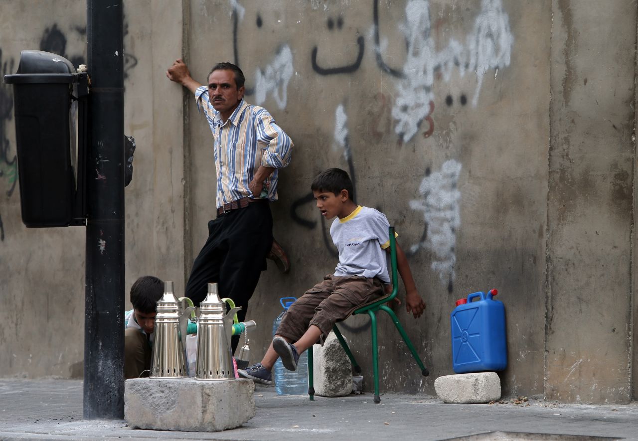 Young Syrian refugees sit with their father as he prepares coffee to sell on a street in Beirut in September 2013.
