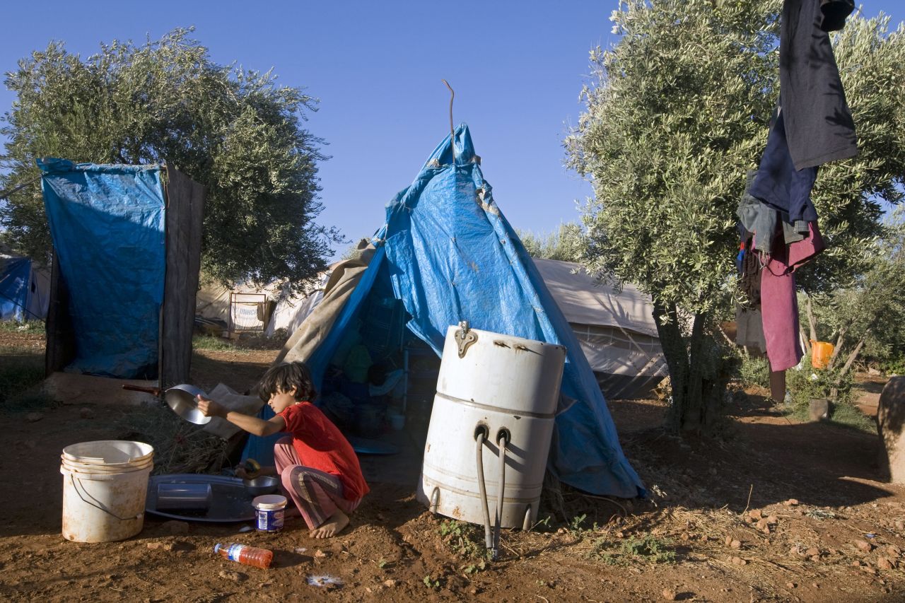 A young Syrian girl washes a pan at the Atme refugee camp along the Turkish border in September 2013.