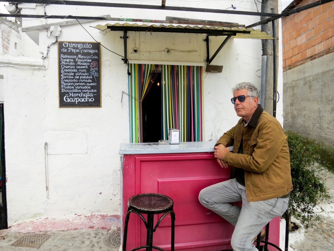 Anthony Bourdain awaits service outside of a cafe featuring traditional Spanish cuisine including gazpacho, ham, cheese and the iconic tortilla: an open-faced potato omelet.