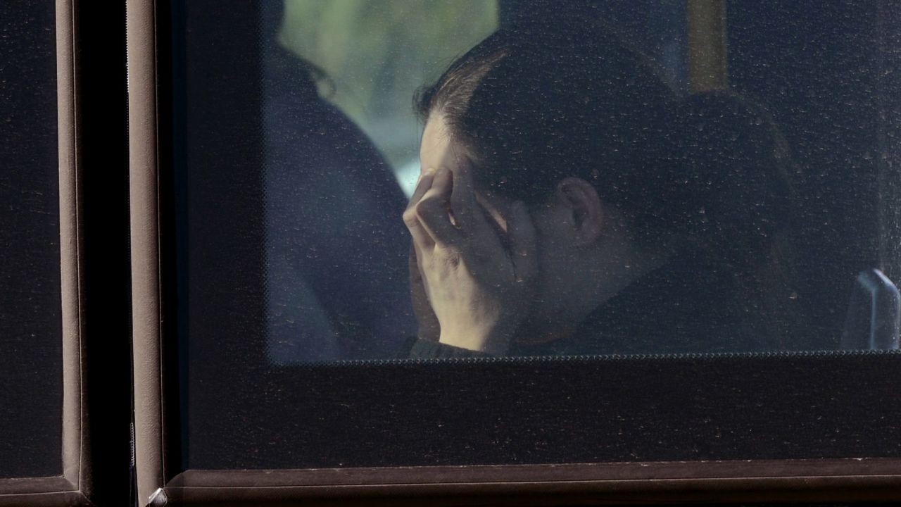 A woman holds her head while sitting on a bus transporting those who were involved in the crash on September 18.