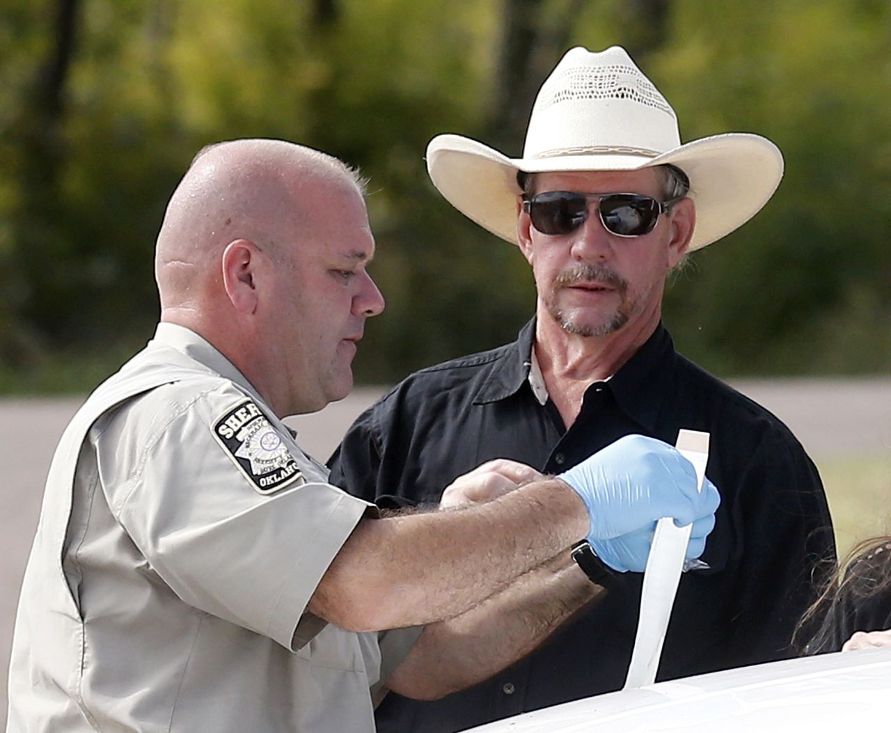 Tim Porter, right, talks with Beckham County Sheriff's Deputy J. Kessel after giving a DNA sample at the scene in September 2013. Porter believed his grandfather's remains were in one of the cars.