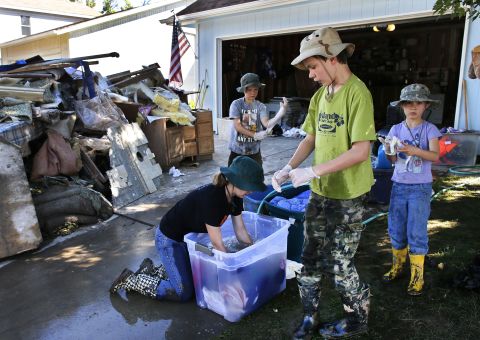 From left, siblings Elizabeth, 13, Jonathan, 9, Aaron, 11, and Kitty Dipert, 6, wash mud from the clothing of family friends from church on September 18 in Longmont, Colorado.