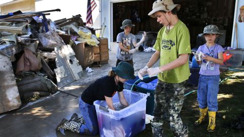 From left, siblings Elizabeth, 13, Jonathan, 9, Aaron, 11, and Kitty Dipert, 6, wash mud from the clothing of family friends from church on September 18 in Longmont, Colorado.