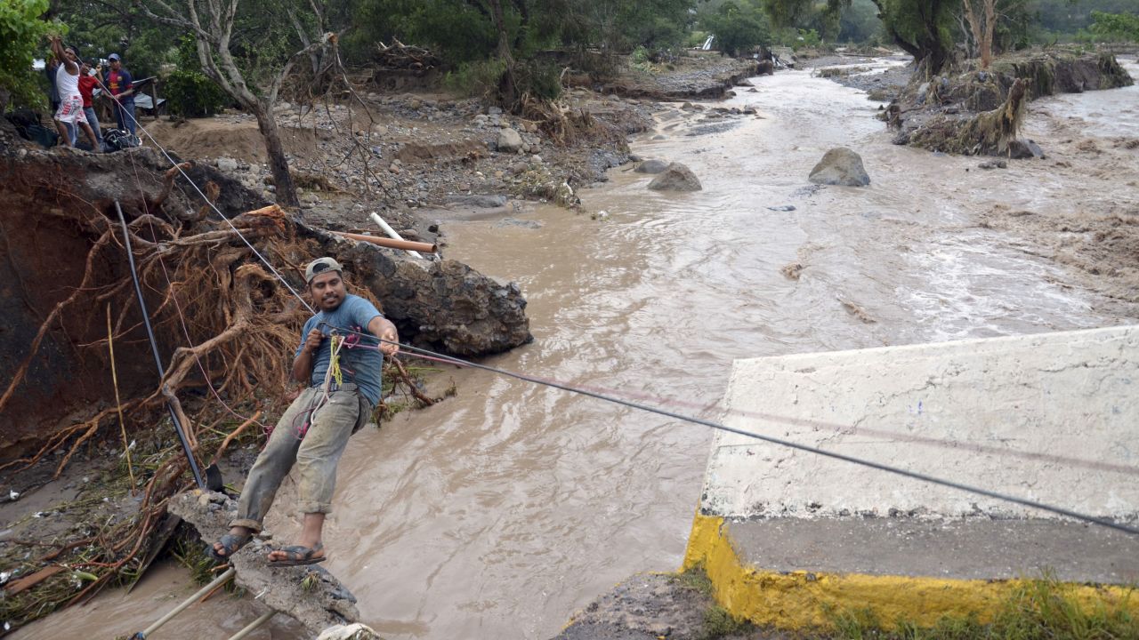 A man crosses a river using a makeshift zip line on September 18, after a bridge collapsed near the town of Petaquillas, Mexico.