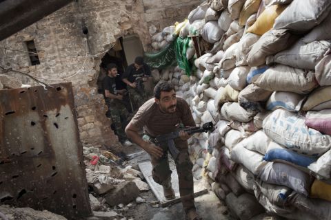 Rebel fighters duck behind a barricade from firing in Aleppo on Wednesday, September 18.