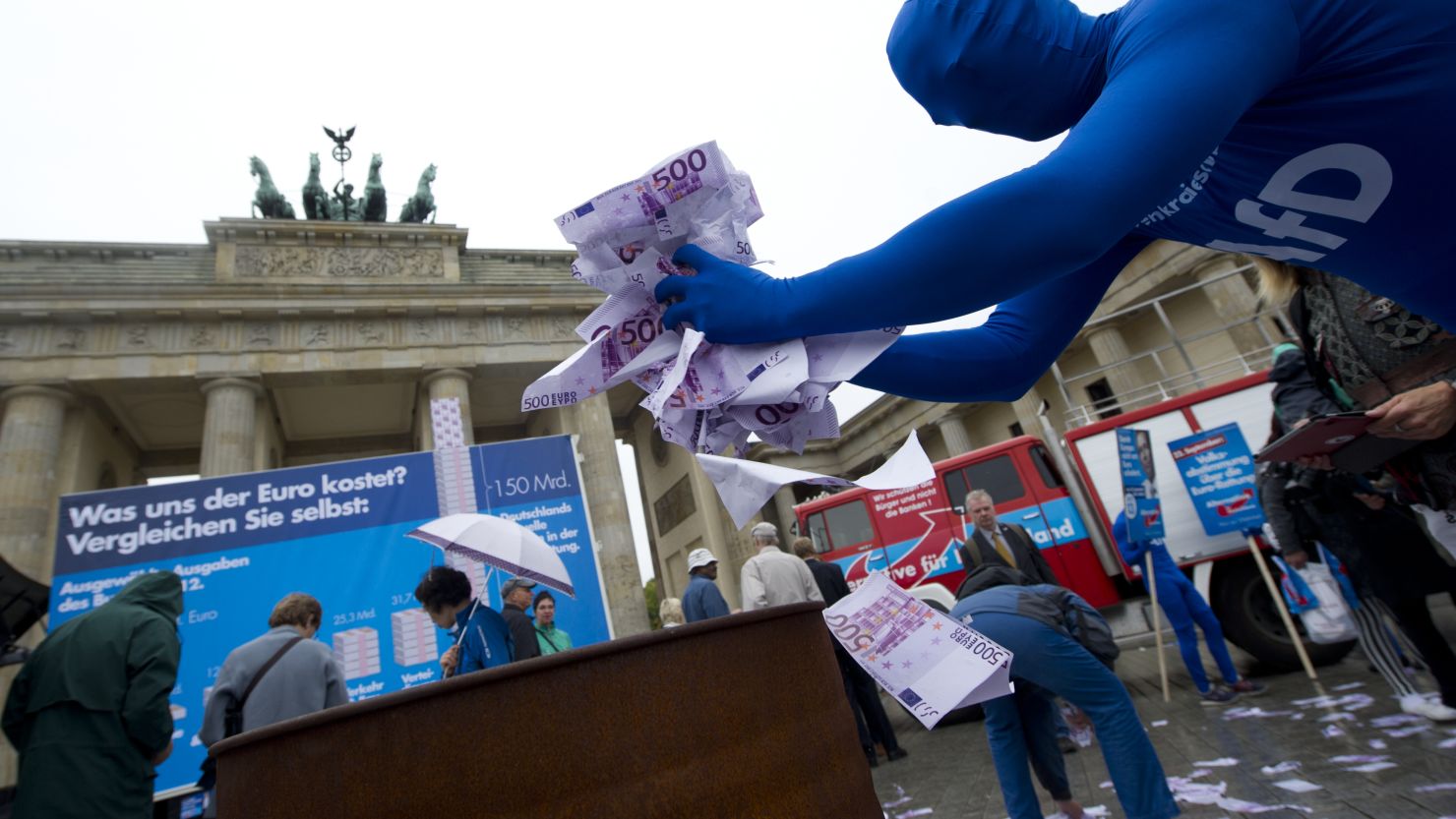 Fake euro notes are thrown onto a fire at a rally for anti-euro party Alternative for Germany (AfD) at Berlin's Brandenburg Gate.