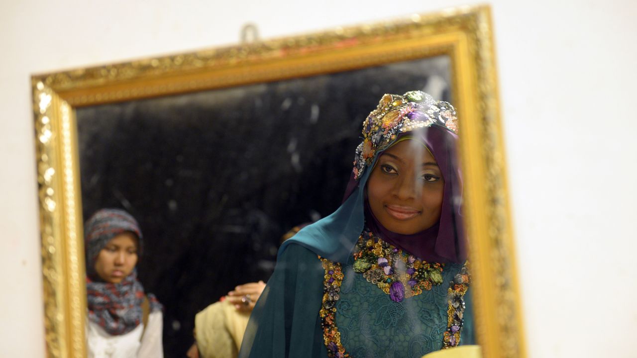 Obabiyi Aishah Ajibola of Nigeria checks her makeup in a mirror during the competition.