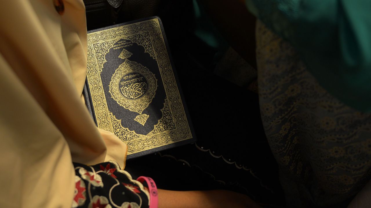 A contestant holds a copy of the Quran backstage.