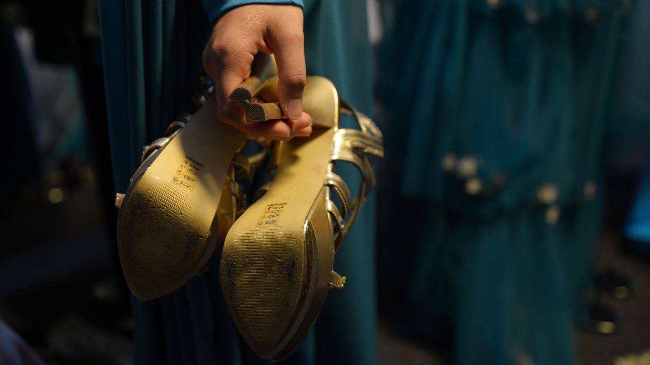 A contestant holds a pair of shoes backstage.