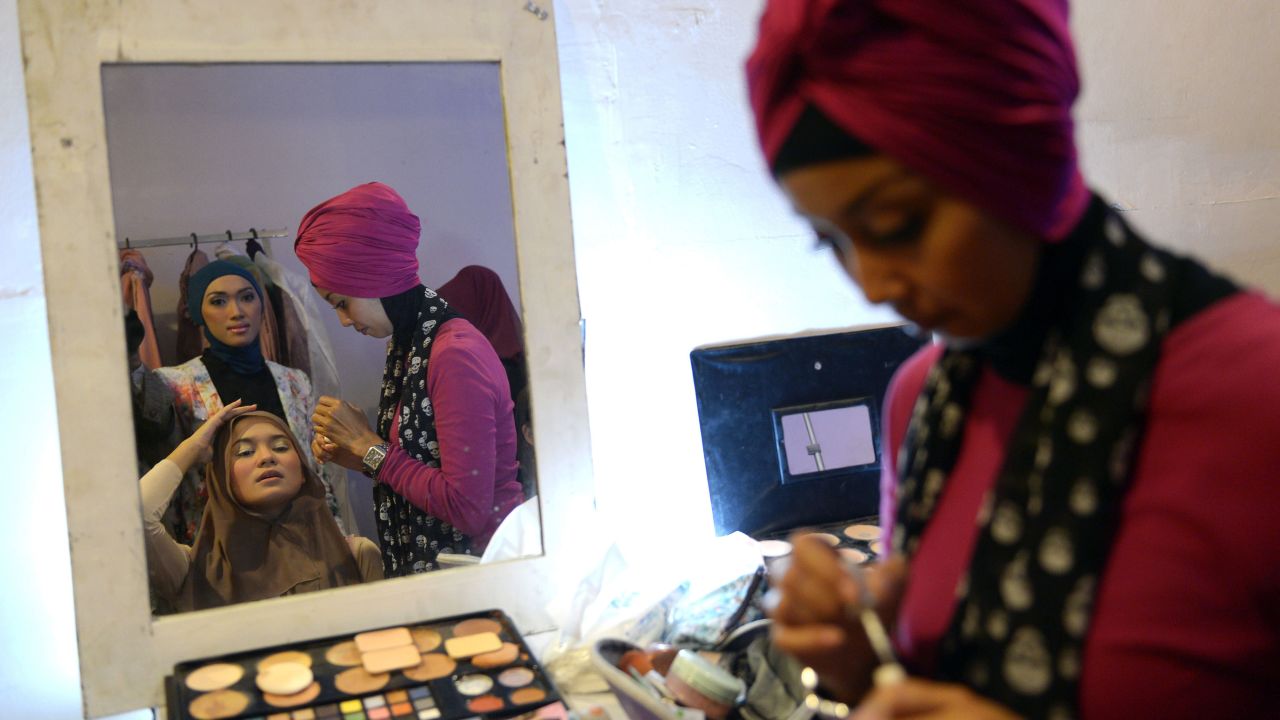 A woman applies make-up to a contestant.