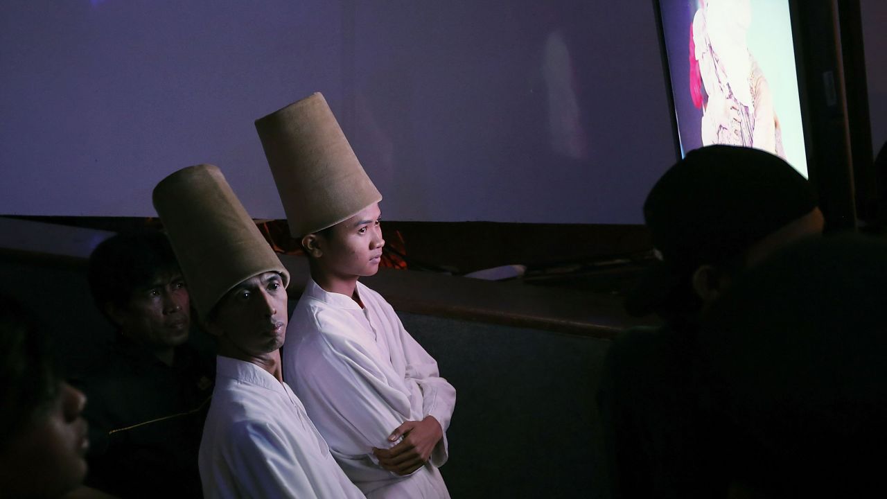 Sufi Muslim dancers watch a monitor offstage during the competition.