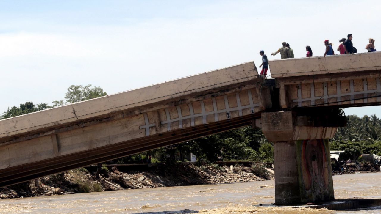 People attempt to cross a collapsed bridge in Coyuca de Benitez on September 18.