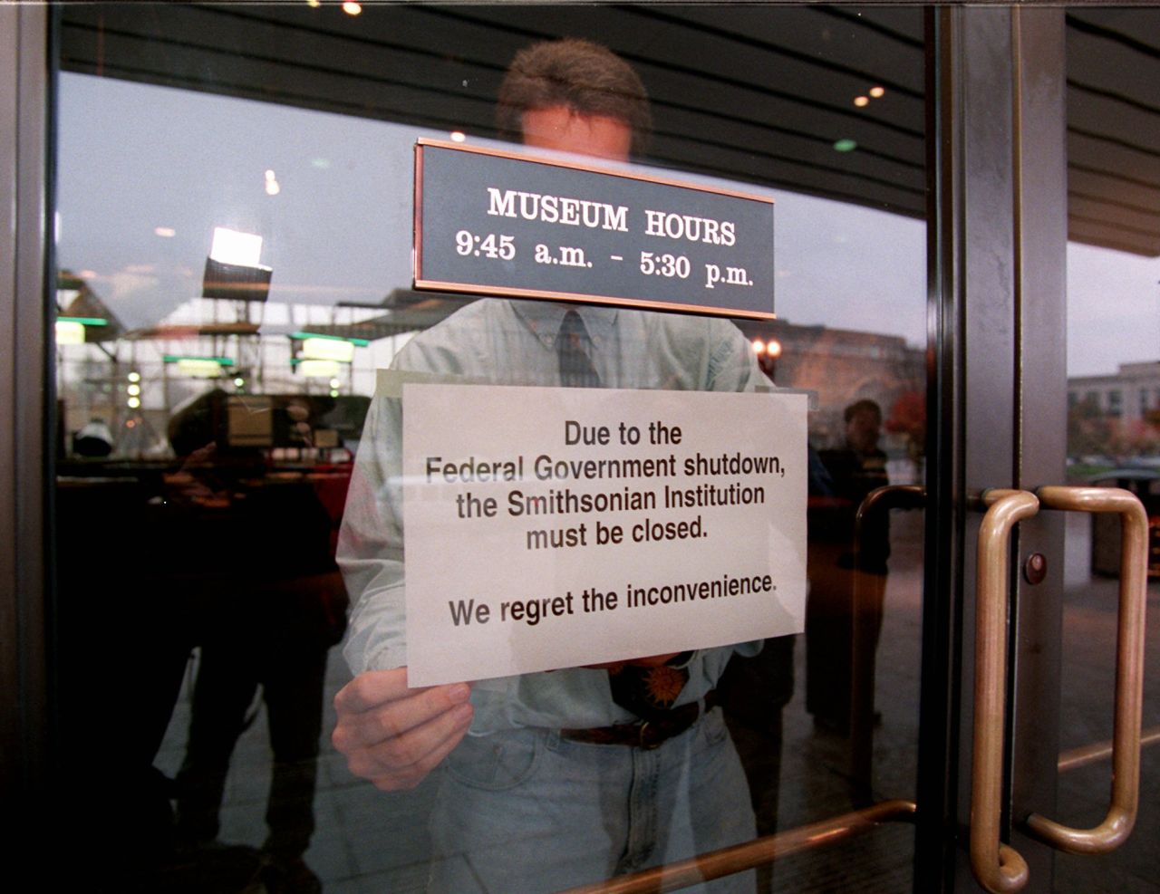 An employee hangs a sign on the door of the Smithsonian's National Air and Space Museum in Washington on November 14, 1995, marking the start of the government shutdown.