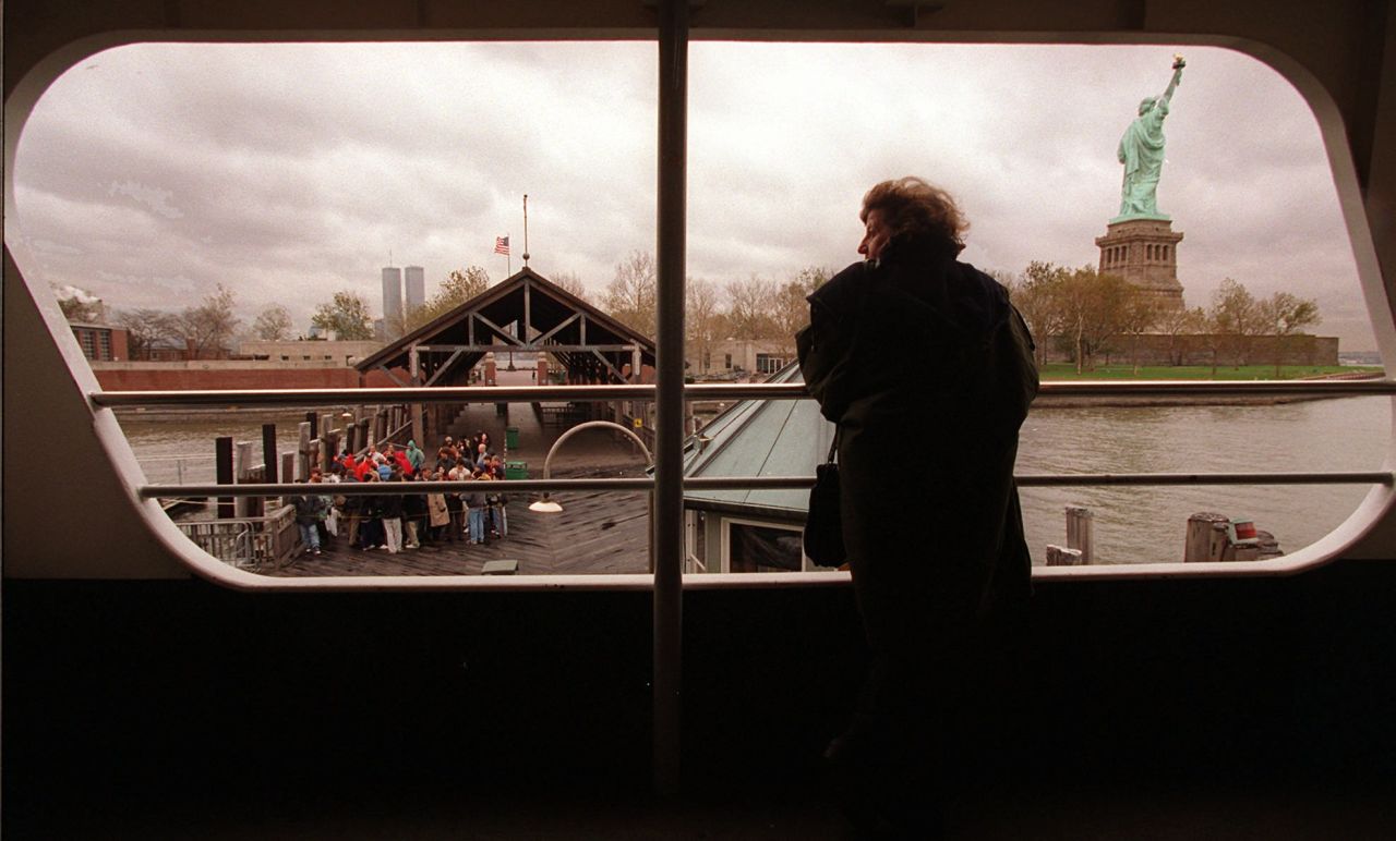 A tourist peers out a ferry window at the Statue of Liberty on November 14, 1995, as a small group of visitors wait on the dock to board the vessel. No passengers were allowed off the boat as both the Statue of Liberty and Ellis Island were closed after federal workers were sent home.