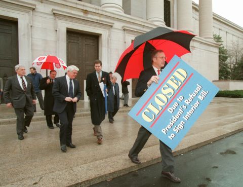 House Appropriations Committee Chairman Rep. Bob Livingston, right, holds a "closed" sign outside the National Gallery of Art in Washington on December 18, 1995.