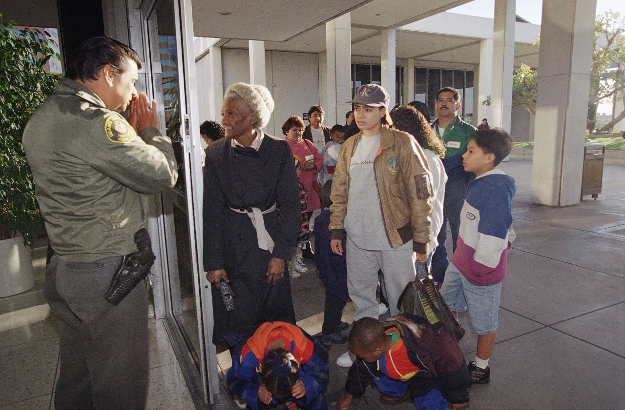 A security guard informs people that the passport office is closed at the Federal Building in Los Angeles on December 18, 1995.