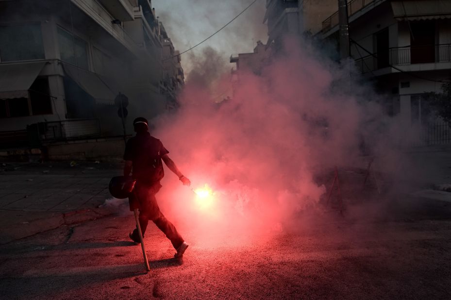 A protestor lights a flare as anti-fascist demonstrators clash with riot police in Athens on September 18, 2013.