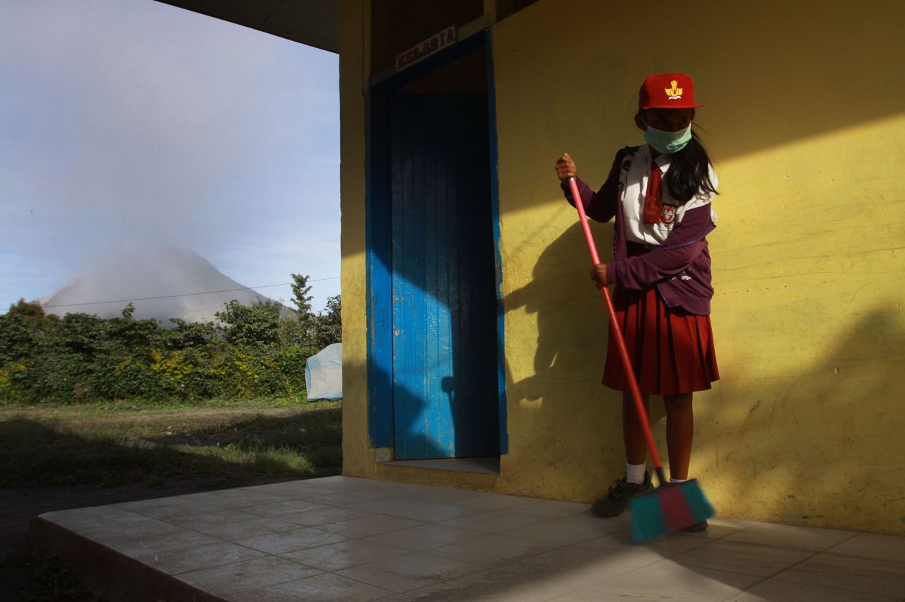 An Indonesian student sweeps volcanic ash from the school hallway in Indonesia's Karo district on September 16 while the Mount Sinabung volcano emits steam and ash. 