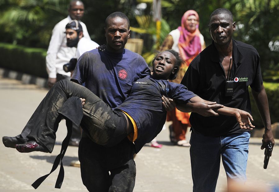 A Kenyan woman is helped to safety after the masked gunmen stormed the upscale mall and sprayed gunfire on shoppers and staff. 