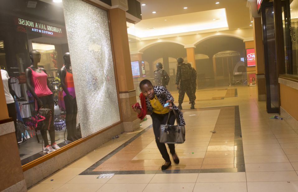 A woman who had been hiding during the attack runs for cover after armed police enter the mall. 