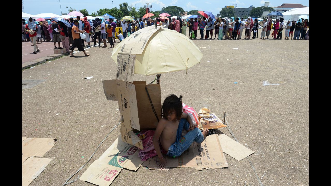 A young evacuee, one of the thousands affected by the standoff between Philippine government forces and Muslim rebels, takes shelter from the scorching heat as others queue up for food distribution at an evacuation center inside a sports complex in Zamboanga, on the southern Philippine island of Mindanao, on September 20.