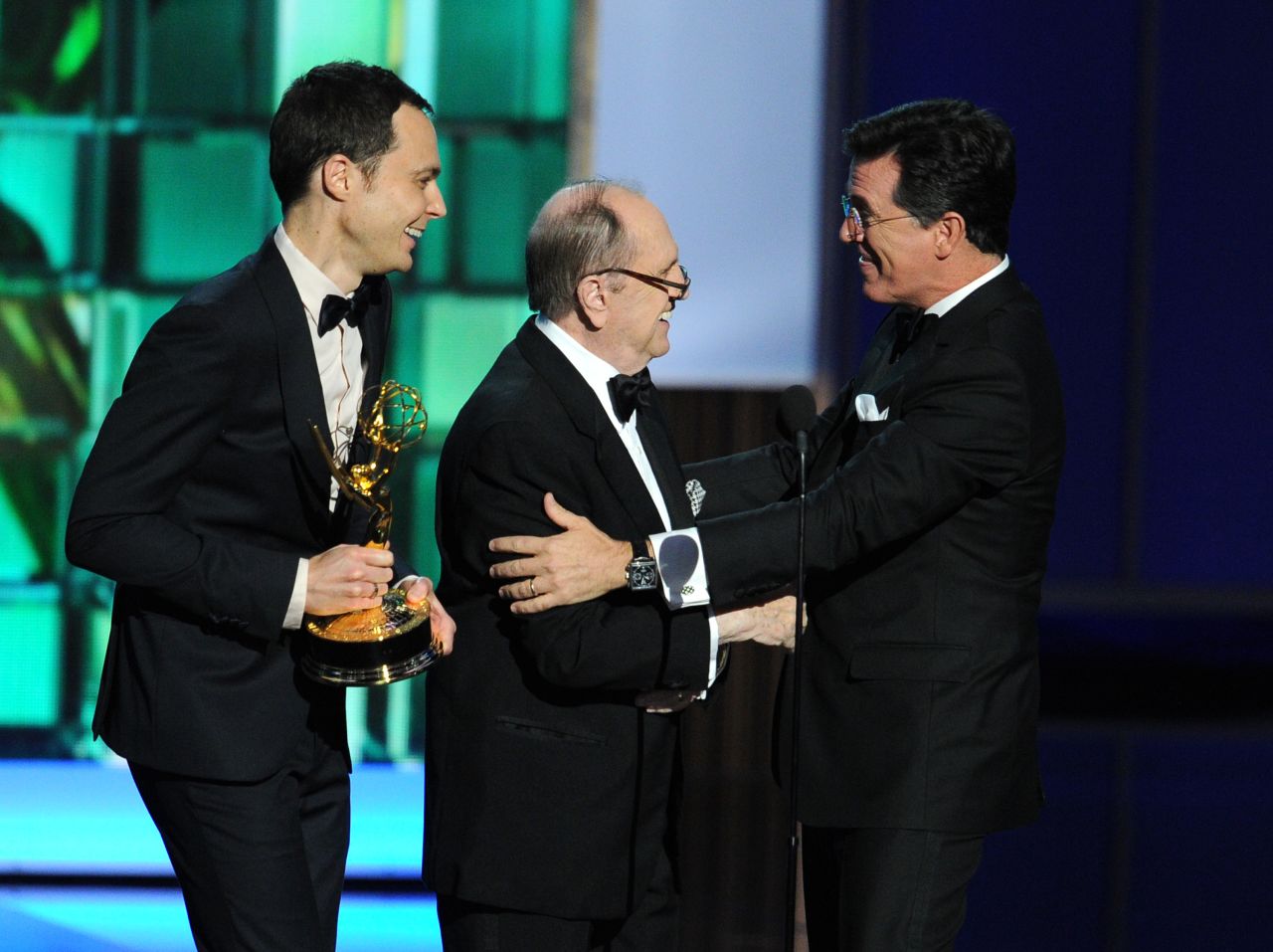 Actors Jim Parsons, left, and Bob Newhart present an award to Stephen Colbert. His show won outstanding variety series and outstanding writing for a variety series.