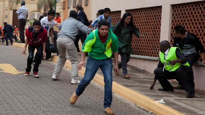 People take cover outside the Westgate Mall in Nairobi after heavy shooting started Monday, Sept. 23, 2013. Kenya's military launched a major operation at the upscale Nairobi mall and said it had rescued "most" of the hostages being held captive by al-Qaida-linked militants during the standoff. (AP Photo/Sayyid Azim)