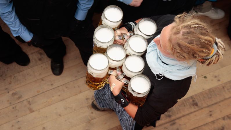 A waitress delivers mugs of beer after tapping the first barrel.