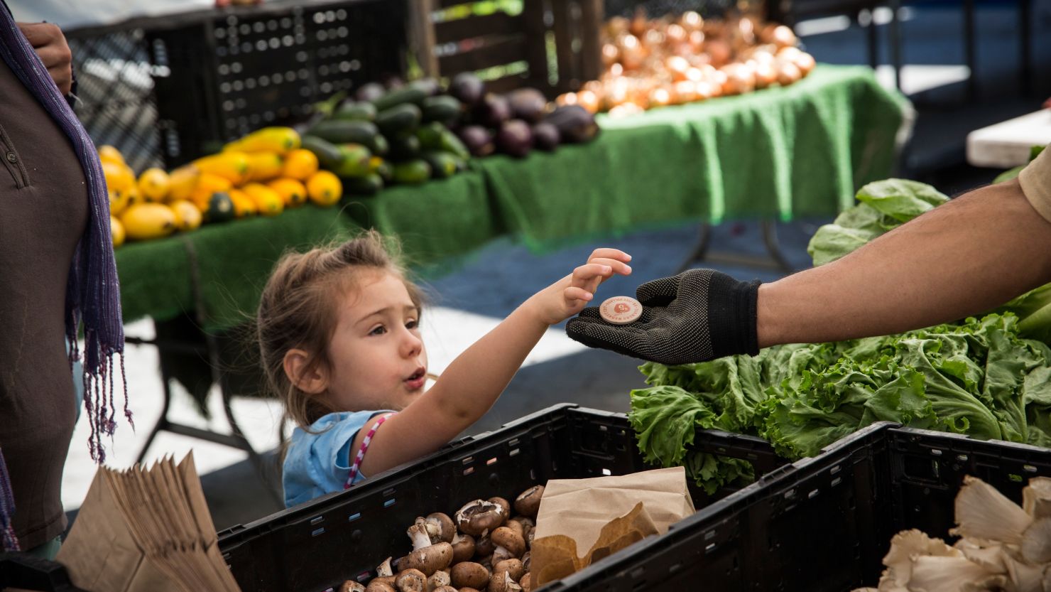 A girl pays for her mom's groceries with a food stamp token at a market in New York's Union Square last week. 