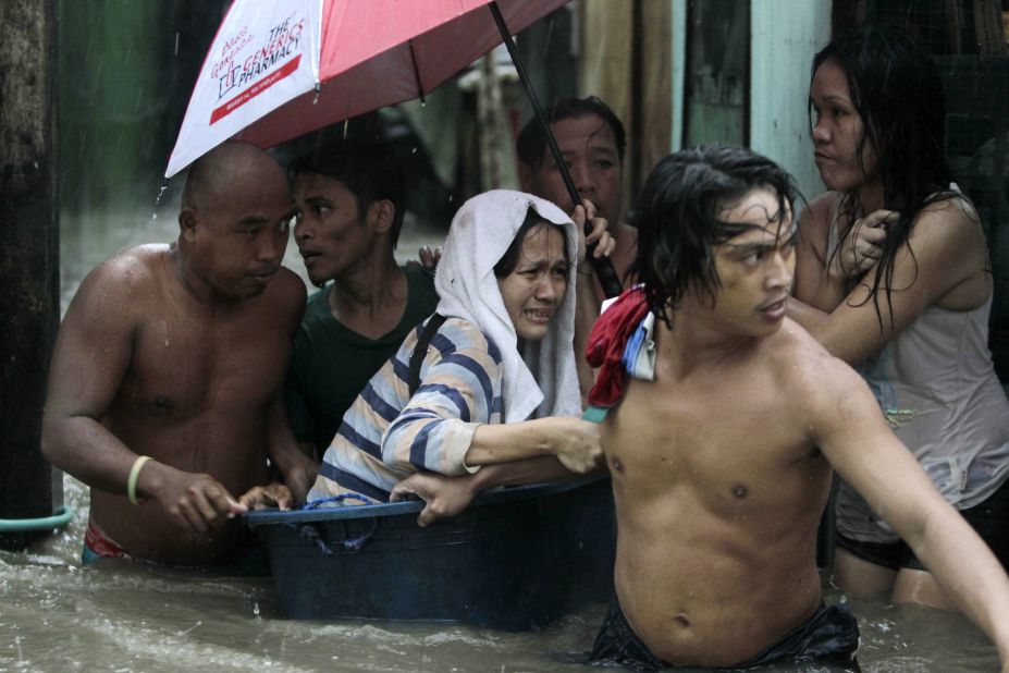 Filipino residents rescue a woman from rising floodwaters in Las Pinas City, Philippines, on Monday, September 23.  More than a dozen people were killed in the Philippines on Monday as heavy rains from Typhoon Usagi battered the main island of Luzon. The storm forced the relocation of hundreds of thousands of people, the cancellation of hundreds of flights and the closing of a major shipping lane. Also, at least 25 people are reported killed in southern China.