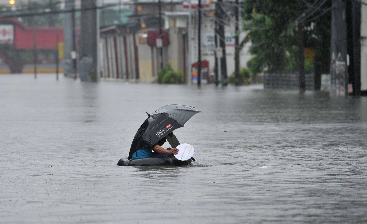 A resident using an inner tube as a makeshift raft paddles through chest-deep floodwaters along a street in Manila on September 23.