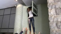 An image grab taken from AFP TV shows a Kenyan woman coming out of an air vent where she was hiding during an attack by masked gunmen at a shopping mall in Nairobi on September 21, 2013.