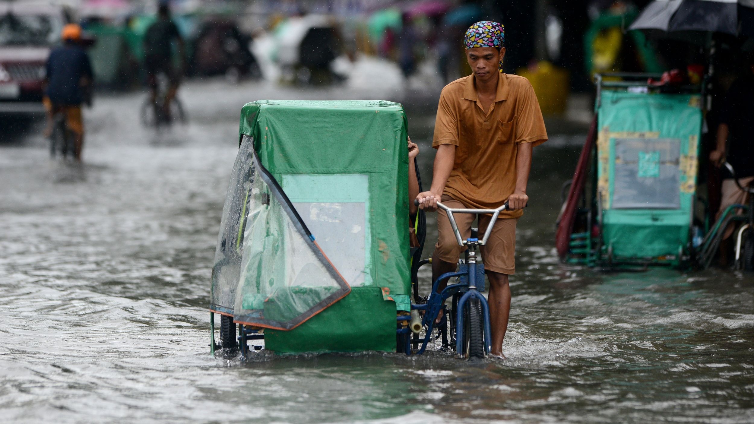 A pedicab driver wades through a flooded street in Manila on Monday.