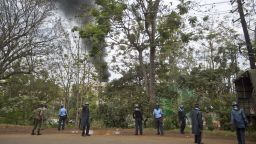 Kenyan police order bystanders and media away from an overlooking hill as a plume of black smoke billows over the Westgate Mall, following large explosions and heavy gunfire, in Nairobi, Kenya Monday, Sept. 23, 2013. Four large blasts rocked Kenya's Westgate Mall on Monday, sending large plumes of smoke over an upscale suburb as Kenyan military forces sought to rescue an unknown number of hostages held by al-Qaida-linked militants. (AP Photo/Ben Curtis)