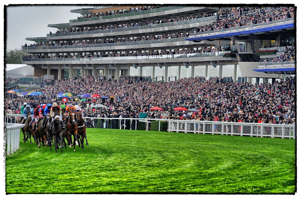 <strong>Royal Ascot, Ascot, Berkshire, UK:</strong> A packed grandstand watches a tightly-bunched group of runners during a race at Royal Ascot in June.  