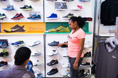 An employee, right, assists a customer selecting sports shoes at a Nike retail outlet inside the mall.