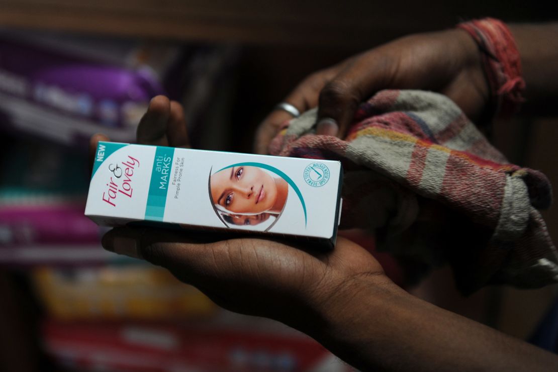A sales assistant holds Fair and Lovely skin fairness cream at a shop in New Delhi.