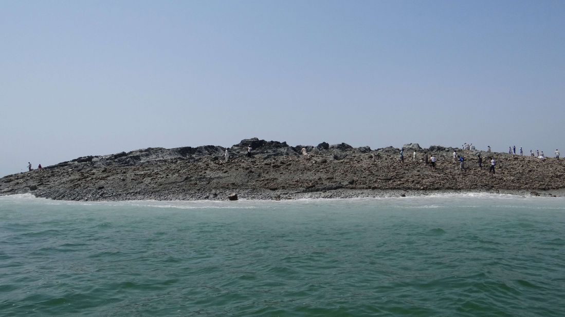 People walk on an island that formed off the coastline of Gwadar after the earthquake hit in this photo released by the Pakistani government.